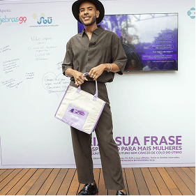 Participante recebe brinde institucional durante evento do Março Lilás