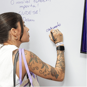 Participante registra mensagem em mural interativo da campanha Março Lilás